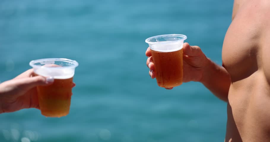 Young man drinking cold beer at beach bar enjoying summer vacation