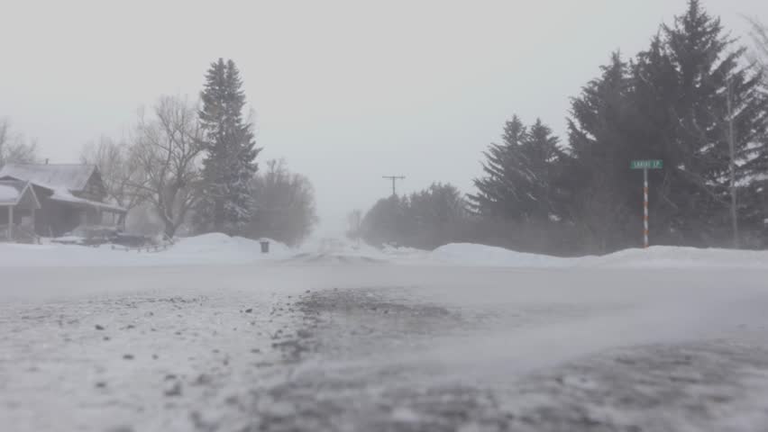 Ground level shot of snow blowing across the edge of the road in a blizzard in Bozeman Montana