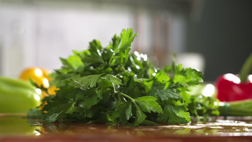 Slow motion of parsley chopped with a knife on wooden board in a kitchen