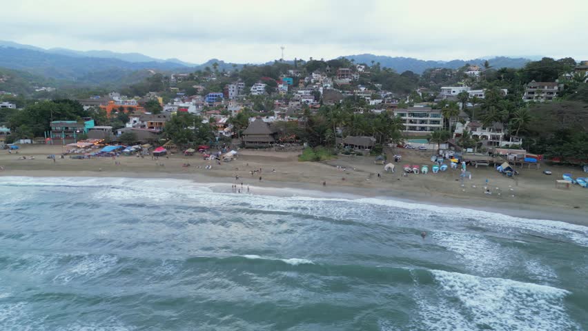 A drone flies overhead showing the beach and town of Sayulita Mexico