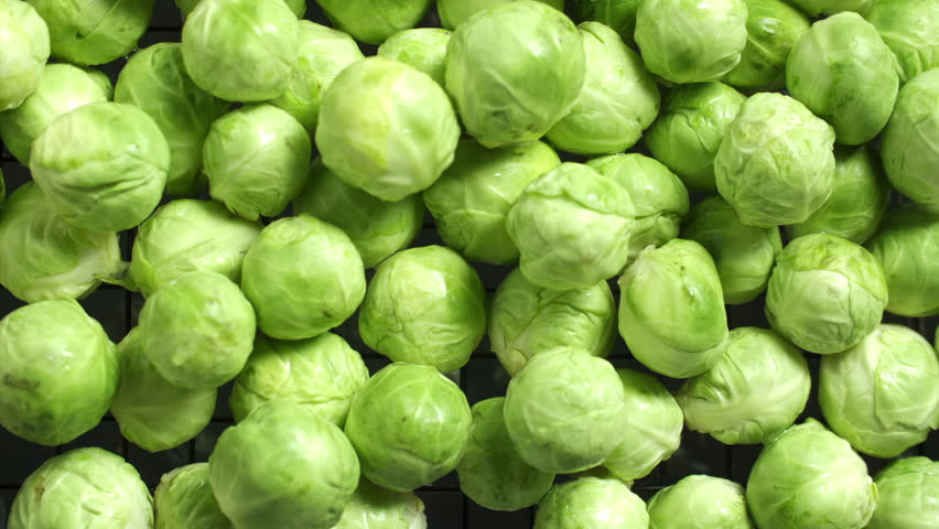 Slow motion of fresh brussels sprouts falling and splashing on water surface