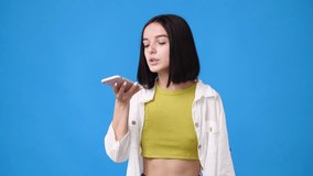 4k video of woman using her phone on blue background.