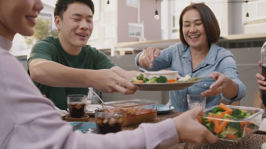 Mom enjoy cooking for family day dining at dine table cozy patio front yard home. Mum passing food serving drink to group four asia people young adult man woman friend fun joy relax warm picnic eating | Shutterstock HD Video #1100815197
