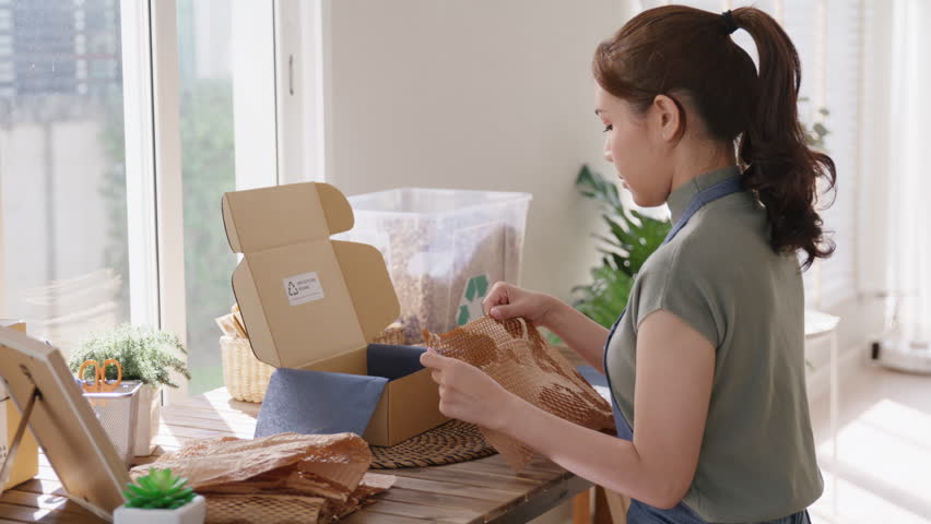 Eco vendor go green packaging parcel carton box in net zero waste store asian seller retail shop. Earth care day small SME owner asia people wrap reuse brown paper pack gift reduce plastic free order. Royalty-Free Stock Footage #1100817897