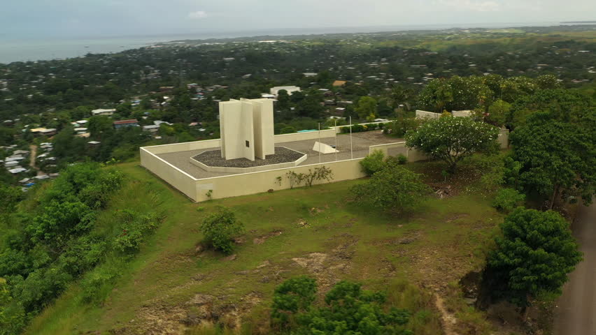 Reverse side panning aerial view of a hilltop monument in outskirts of Honiara.