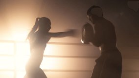 Close-up shot of a woman working out with a personal trainer in the boxing ring. Portrait of sporty couple building muscle strength and burning calories in the gym. High quality 4k footage - Powered by Shutterstock - Get 15% off with code: PIKWIZARD15