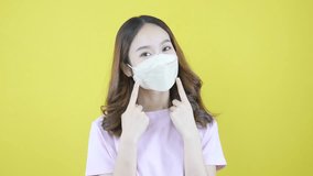 Young Asian woman advised to wear a mask in public on a yellow background. - Powered by Shutterstock - Get 15% off with code: PIKWIZARD15