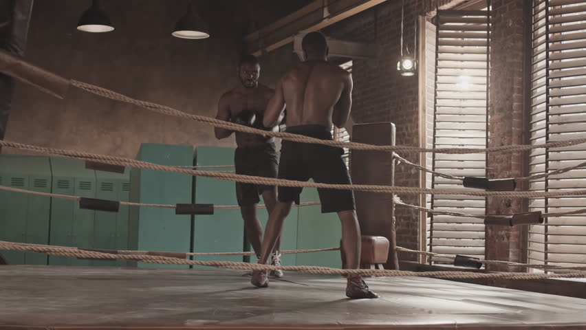 Full-length slowmo shot of two shirtless Black male boxers fighting in ring | Shutterstock HD Video #1100824029
