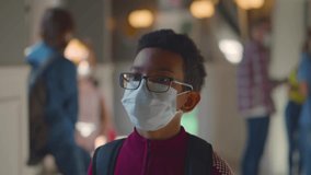 African American boy wearing face mask walking to classroom at school. Teenage schoolboy walk in medical mask studying during coronavirus. Student in safety mask at school. Realtime - Powered by Shutterstock - Get 15% off with code: PIKWIZARD15