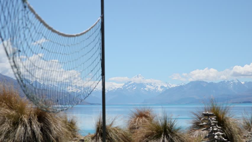 Volleyball net moving in wind with stunning Mount Cook and Lake Pukaki in background; static courtyard view