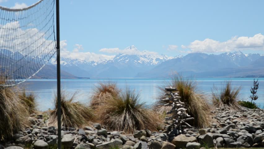 Bushes and a volleyball net with snowy mount cook and blue lake Pukaki in background