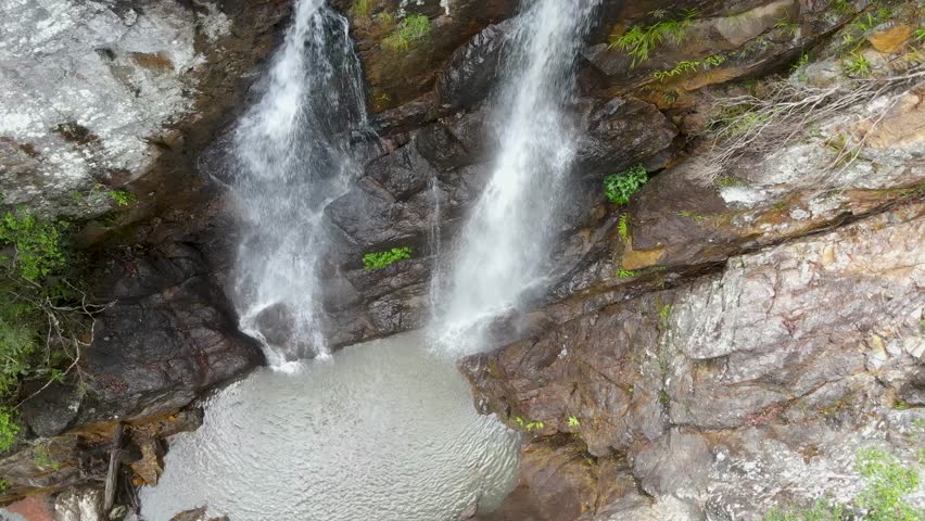Twin waterfalls cascading down into a secluded natural swimming waterhole. Mount Jerusalem National Park Australia