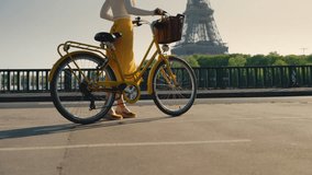 Young girl in a yellow skirt with a bicycle on the bridge near the Eiffel Tower