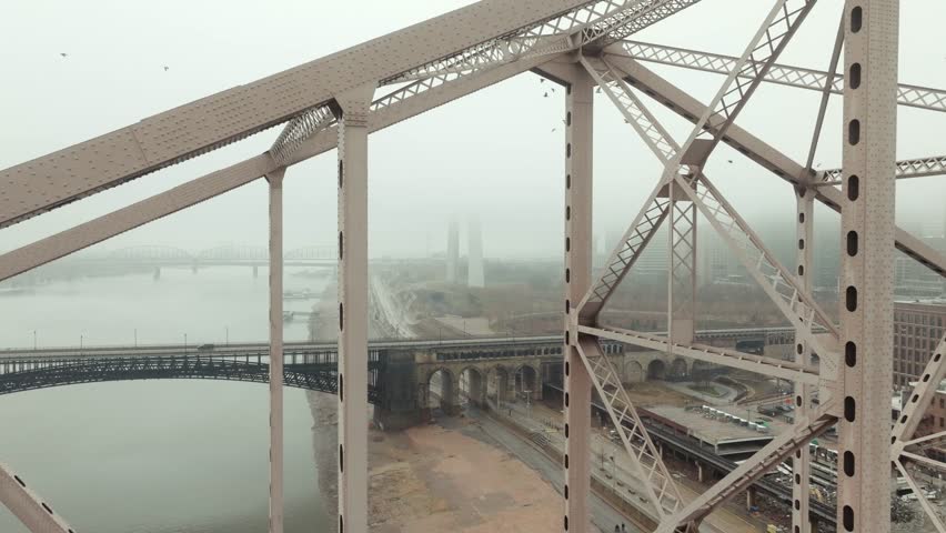 Aerial rise up truss of Martin Luther King Bridge, view of St. Louis in fog.