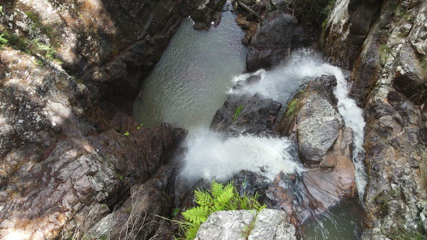 Twin waterfalls cascading down an eroded rock face into a secluded significant indigenous swimming hole