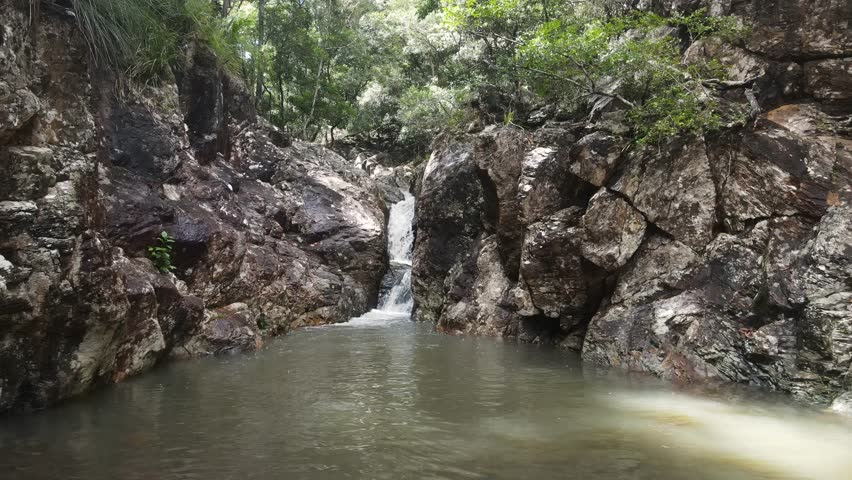 Australian tropical rainforest creek flowing into a indigenous significant watering hole. Slow moving view