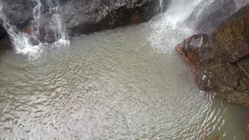 Slow climbing view following a twin cascading waterfalls and secluded natural rock pool.
