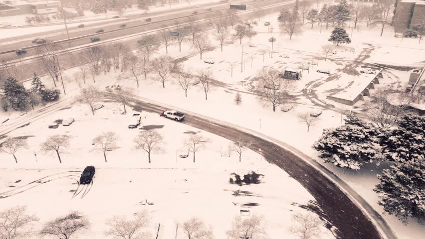 Snowy Highway from Above: A Drone's Eye View. Pick-up truck snow plough removes snow from the street. Royalty-Free Stock Footage #1100843763