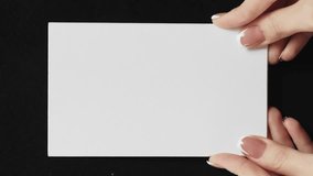 Vertical video. Blank card. Information letter. Female hands showing white mockup paper sheet with empty space on black background set of 2 loop. - Powered by Shutterstock - Get 15% off with code: PIKWIZARD15