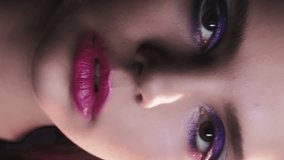 Vertical video. 90s face. Artistic makeup. Old fashion look. Closeup portrait of teen girl with purple color eyeshadow pink lips 2000s retro beauty visage.
