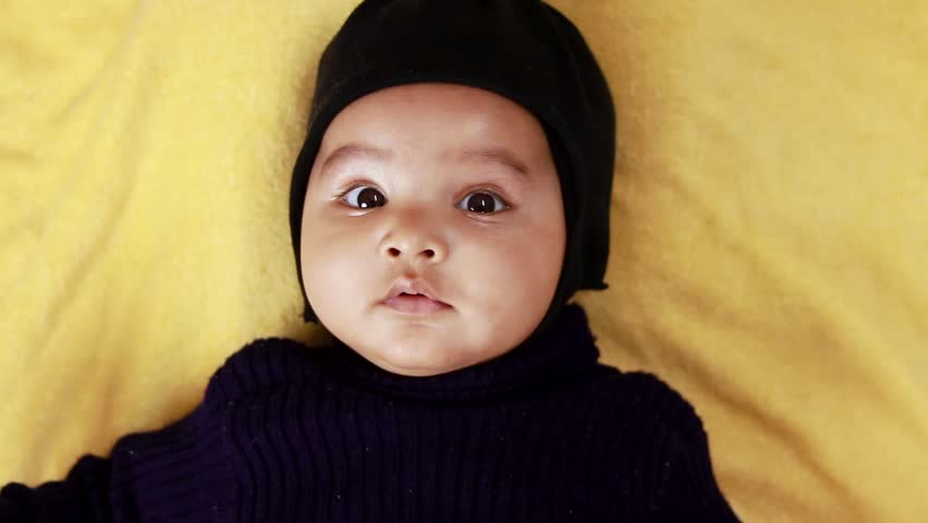infant boy in black outfit lying cute facial expression at indoor from top angle