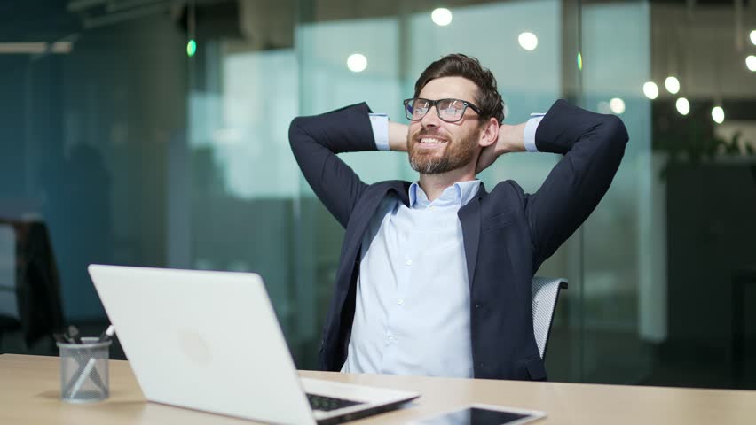 Resting entrepreneur investor with hands behind head feels satisfied with work well done indoor Calm bearded businessman relax after hard working day finished project job on computer at modern office | Shutterstock HD Video #1100847307