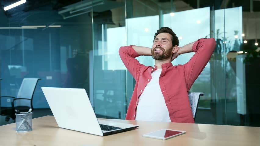 Businessman working at modern office, stretching while taking a break at desk job Workplace holding hands behind head Office worker finished work feels peace of mind Male takes break to relieve stress | Shutterstock HD Video #1100847317
