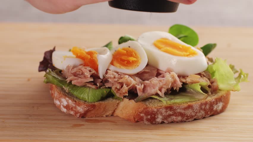 Chef cooking tuna sandwich, cook preparing a tuna eggs salad sandwich at the ingredient station of a cafe restaurant kitchen.