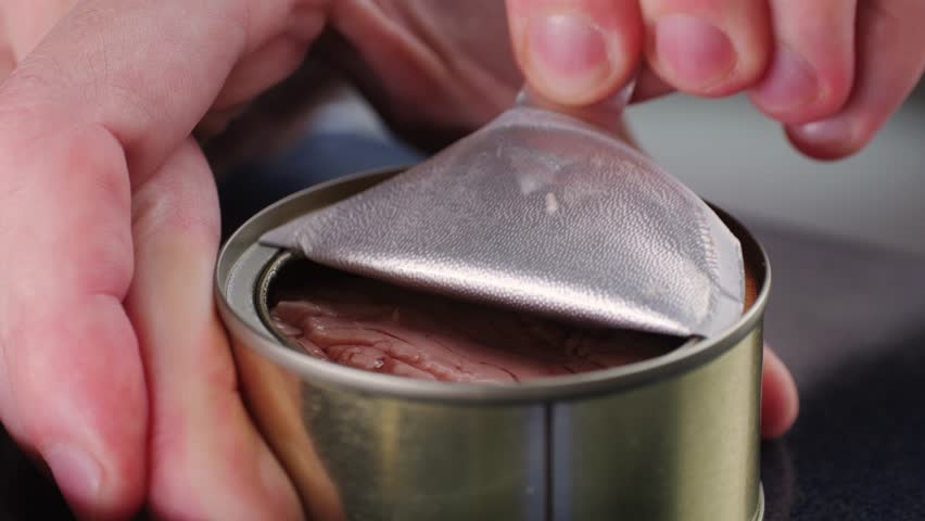 Opening tuna can, man open the canned tuna on the table. Close up on professional kitchen.