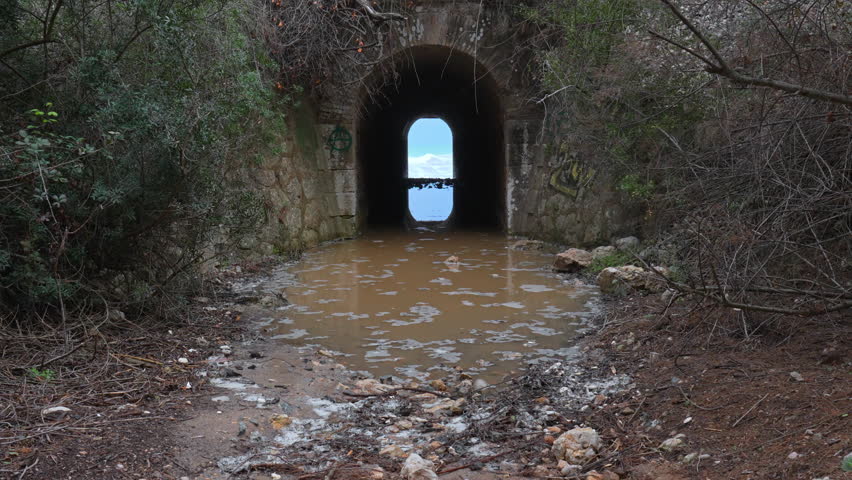A tunnel leads towards a wild sea, where incoming waves create a rippling effect
