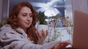 (Camera: ARRI ALEXA, real time) A young caucasian woman is working from home, cozy with a blanket, sipping coffee or tea, happy. For more variations of this clip, check out this seller's other videos.