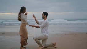 Amorous lovers engaging at sunset seashore. Handsome man making surprise marriage proposal to beloved woman at evening beach. Rejoicing girl saying yes. Emotional moment. Relationship goals concept - Powered by Shutterstock - Get 15% off with code: PIKWIZARD15