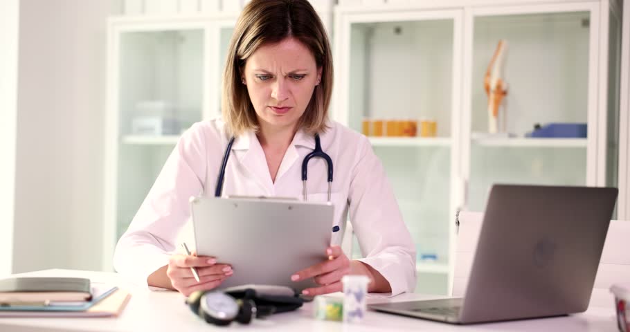 Doctor examines medical documents at workplace in clinic | Shutterstock HD Video #1100855539