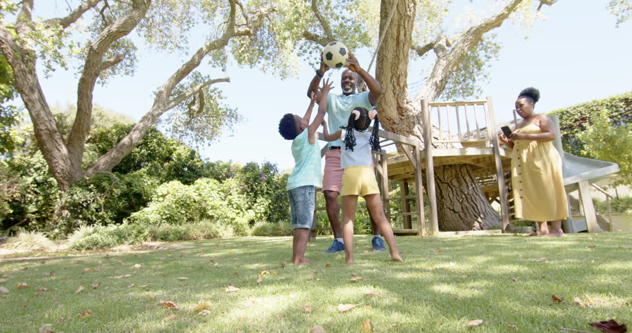 Happy african american grandparents with grandchildren playing football in garden, in slow motion. Spending quality time at home concept. Royalty-Free Stock Footage #1100856109