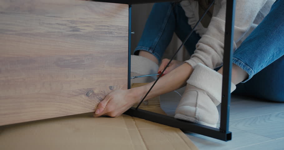 Young woman assembling furniture in her new home, assembling flat pack furniture DIY