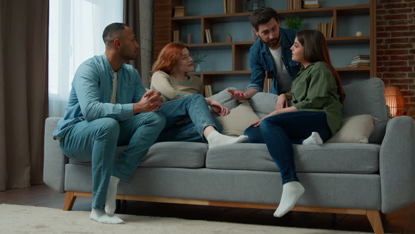 Group ethnic people friends talking discussing future plans at home meeting diverse multiracial women and men sit on comfortable sofa chatting friendly communication spending weekend together at home Royalty-Free Stock Footage #1100866827