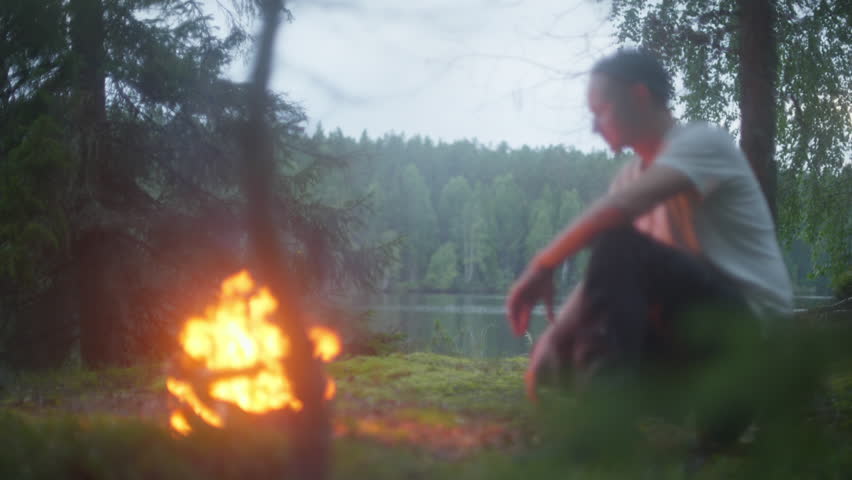 Man sitting infront of fire in the woods