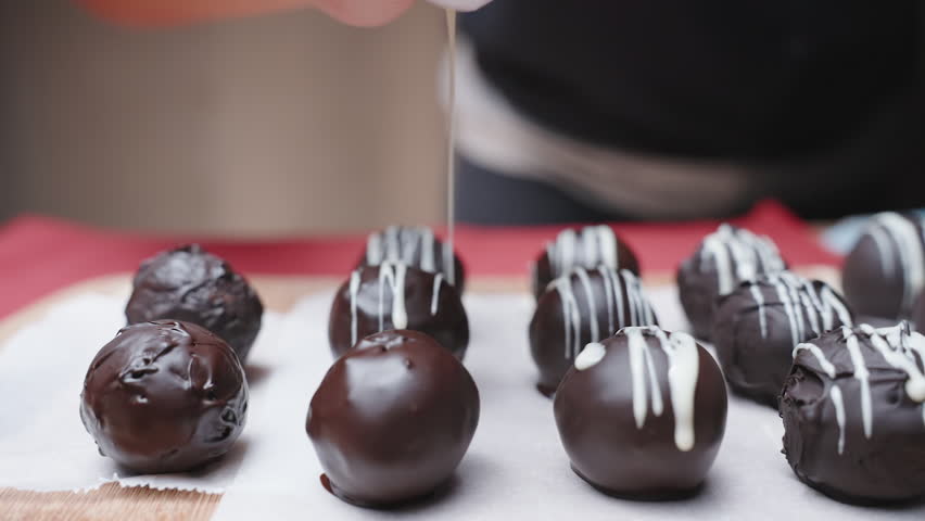 Homemade chocolates are made by hand. I pour them with white chocolate, slow-motion.