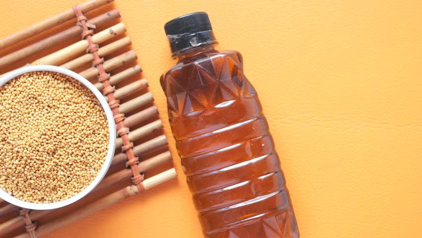 Mustard oil in a plastic jar and seeds in a container 