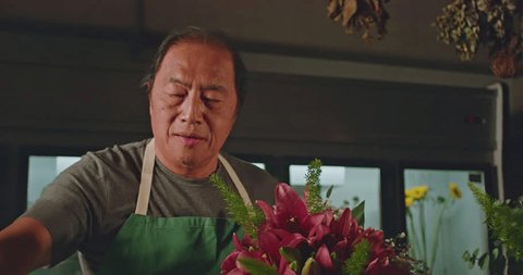 Happy entrepreneur of small business flower shop creating bouquet arrangement of flowers: film stockowy