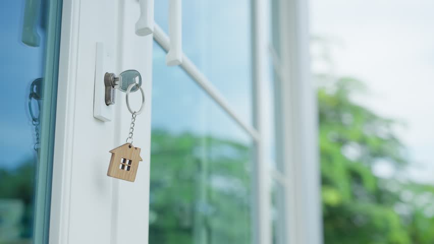 Landlord key for unlocking house is plugged into the door. Second hand house for rent and sale. keychain is blowing in the wind. mortgage for new home, buy, sell, renovate, investment, owner, estate Royalty-Free Stock Footage #1100879587