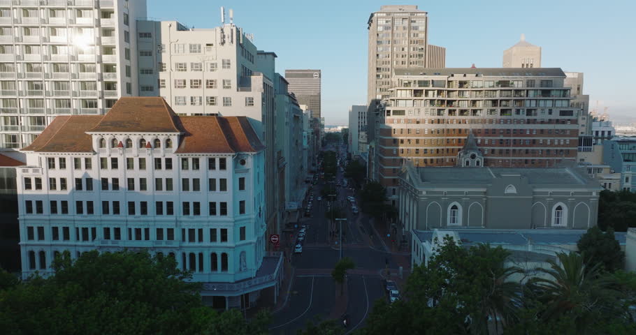 Fly above street in city centre. Church and office of apartment buildings. Cars parking along road. Cape Town, South Africa