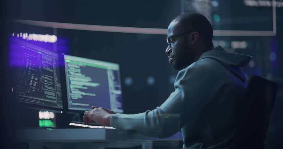 Black Male Programmer Working in Monitoring Room, Surrounded by Big Screens Displaying Lines of Programming Language Code. Portrait of Man Creating a Software. Abstract Futuristic Coding Concept | Shutterstock HD Video #1100883683