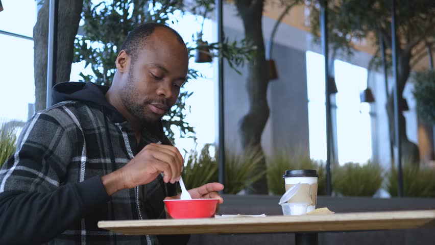a black man eats from disposable tableware in a stylish eco cafe