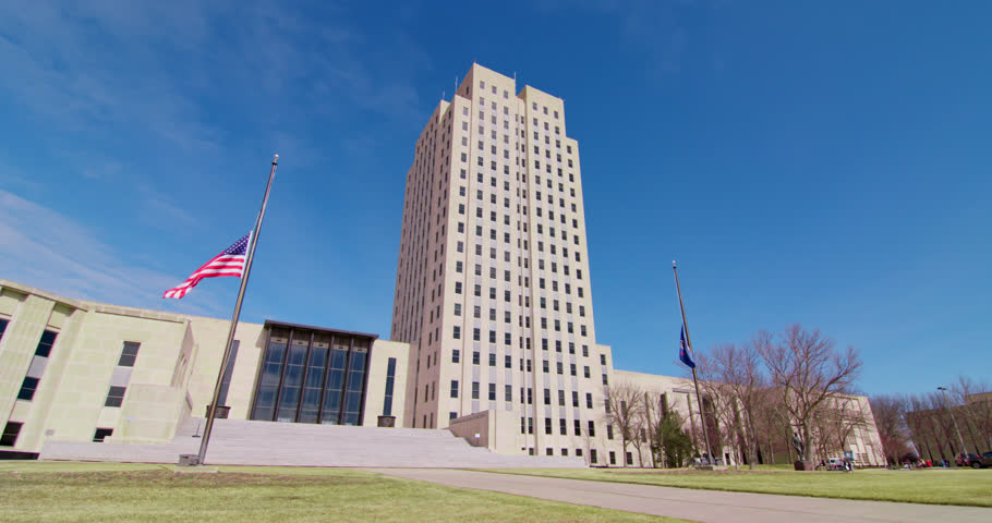 North Dakota State Capitol building, North Dakota, United States, Establishing Shot Low Angle with Flags Flying At Half Mask Slow Pan Left Royalty-Free Stock Footage #1100887059