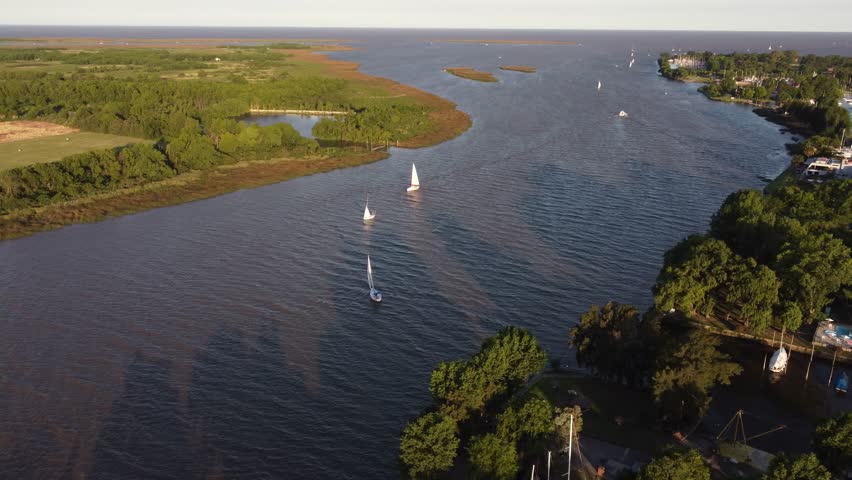 Sailboats navigating along maritime route between Buenos Aires in Argentina and Montevideo in Uruguay, San Isidro Yacht club along Rio de la Plata river at sunset. Aerial drone panoramic view 