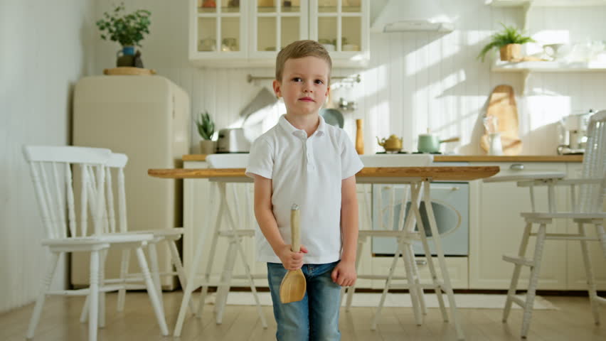 Cheerful carefree child kid boy is dancing and singing with spatula in kitchen. | Shutterstock HD Video #1100894603