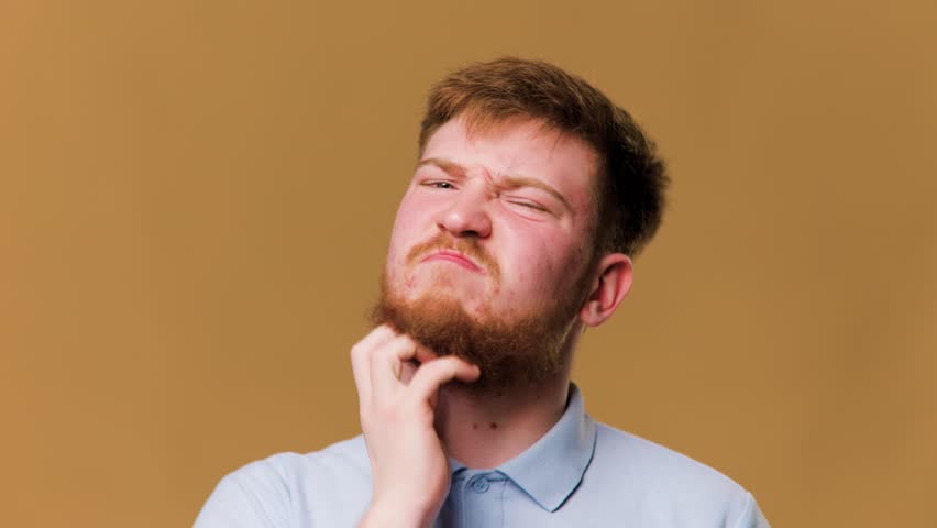 A redhead guy in a studio shot, suffering from an allergic reaction and scratching Royalty-Free Stock Footage #1100894653