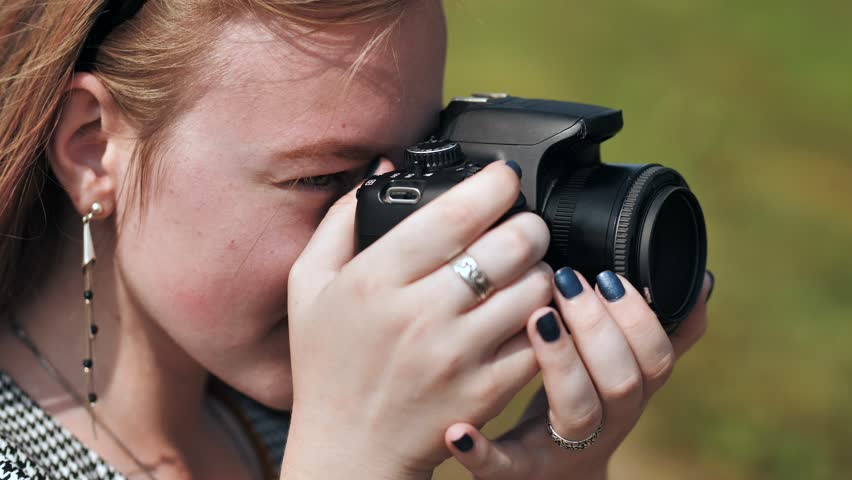 A girl taking pictures with her camera on a summer day.
