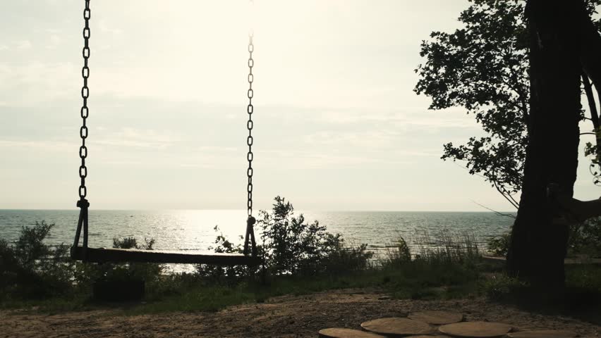 girl rides on a swing against the background of the sea slow motion